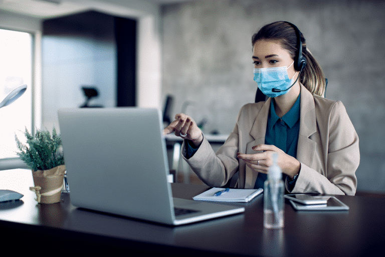 businesswoman-with-face-mask-analzying-paperwork-while-having-video-conference-desktop-pc-office-2-768x512